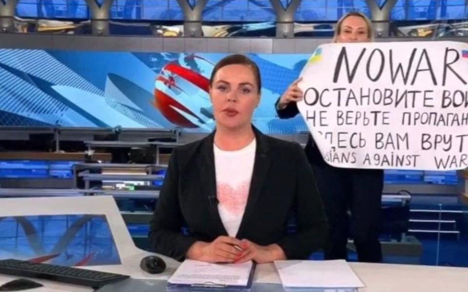 This video grab taken on March 15, 2022 shows Russian Channel One editor Marina Ovsyannikova holding a poster reading: "Stop the war. Don't believe the propaganda. They are lying to you" during a live news broadcast, in Moscow, on March 14, 2022. - Handout/AFP