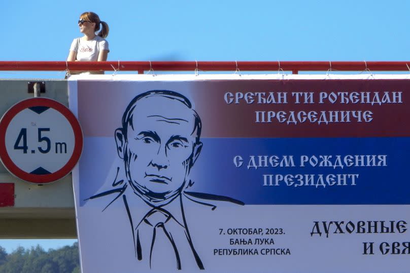 Una mujer camina junto a una valla publicitaria con una imagen de Vladimir Putin, que dice: "Feliz cumpleaños Presidente", en la ciudad bosnia de Banja Luka, octubre de 2023.