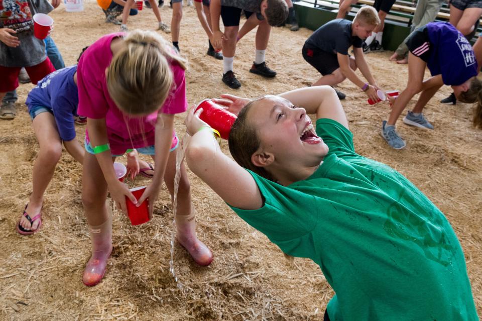 Veronica Orth, left, pours out a cup of water while attempting to fill Alivea Leek’s cup while competing in the over-under event during the Livestock Barn Olympics at the 100th Vanderburgh County Fair Monday afternoon, July 26, 2021.