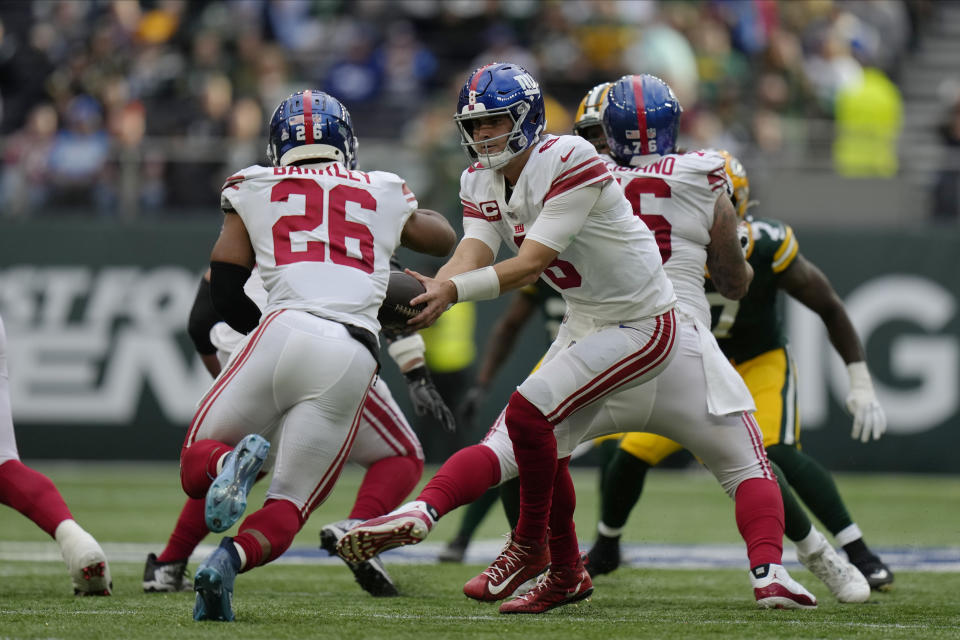 New York Giants quarterback Daniel Jones (8) hands off the ball to running back Saquon Barkley (26) during the second half of an NFL football game against the Green Bay Packers at the Tottenham Hotspur stadium in London, Sunday, Oct. 9, 2022. (AP Photo/Alastair Grant)