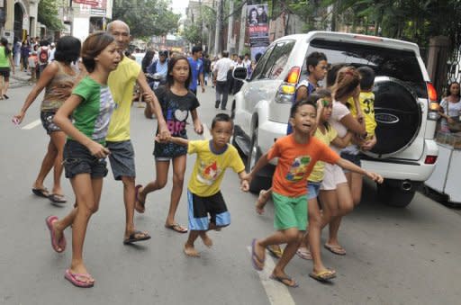 Residents run to safety after a 6.8 earthquake that hit Cebu City on February 6, 2012. Local military chiefs said 43 people were confirmed killed, but officials warned the death toll may rise. Dozens of others are feared injured or missing with landslides having blocked roads for rescuers in mountainous areas