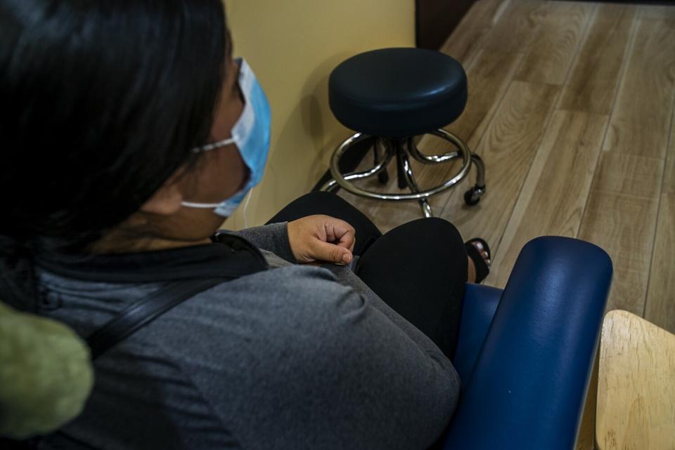 Woman wearing mask sits on a chair.