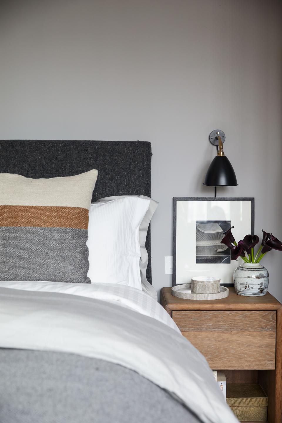 The bedding is from Belgian luxury linen company Libeco, and the sanded and smoked oak nightstand was designed by Basmajian. The wall lamp is from Original BTC, and the vase is Chinese 19th century. The photograph is by Karl Hugo Schmölz.