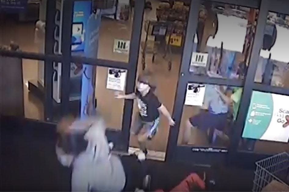 A store surveillance image shows children running away from a gunman at the Collierville Kroger store on September 23, 2021. In the foreground, women have lost their balance as they squeeze through a narrow door. The video shows the women getting back up and escaping. The children all escaped safely.