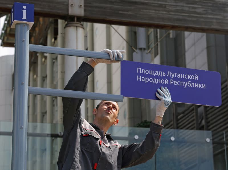 Workers install a direction sign "Luhansk People's Republic Square" in front of the British embassy in Moscow