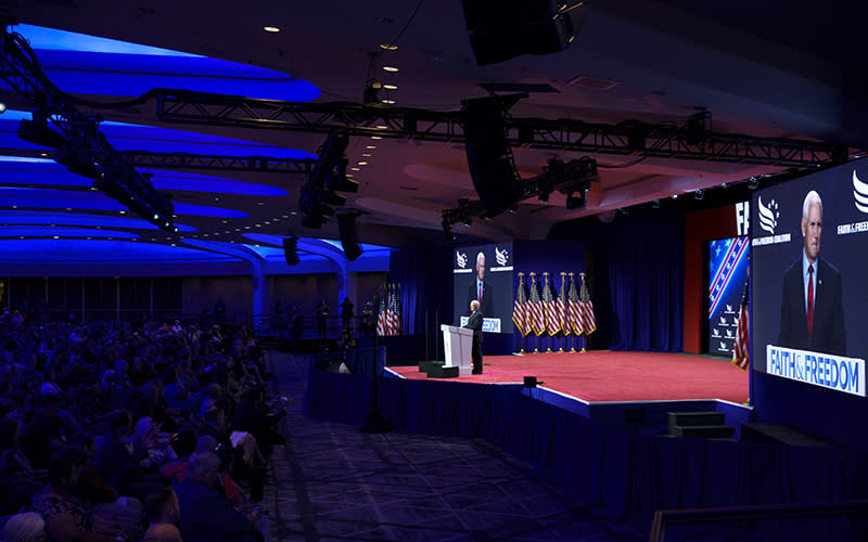 Republican presidential candidate and former Vice President Mike Pence addresses the Faith and Freedom Coalition's Road to Majority conference. The picture is taken from a distance, showing the stage and attendees