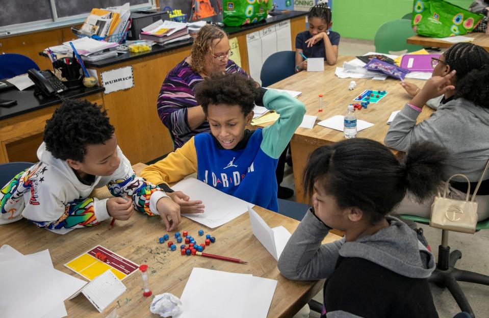 Lucas Wade, 11, of Detroit, left, Jarnell Johnson, 11, of Redford Township, and Aubrie Bell, 10, of Detroit, play a round of WFF’N Proof in preparation for the upcoming Michigan League of Academic Games Super Tournament that will be held in March, after school at Foreign Language Immersion and Cultural Studies School in Detroit on Tuesday, Feb. 6, 2024. Coach LaTrelle Pierre plays in the background with Samiyah Muhhamad, 10, of Detroit, and Malia Small, 13, of Detroit.