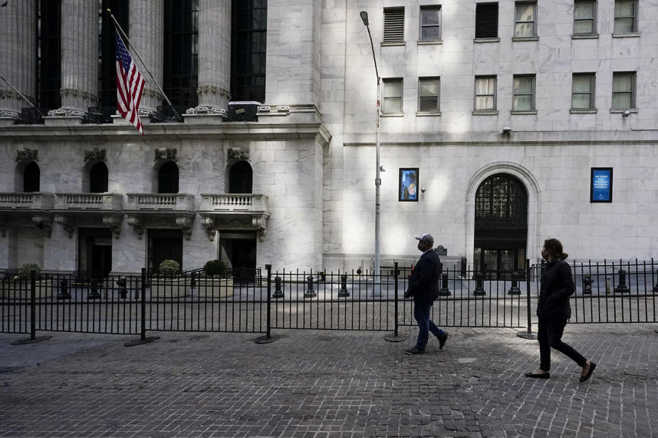 Pedestrians walk past the New York Stock Exchange in the Financial District on March 23, 2021. 