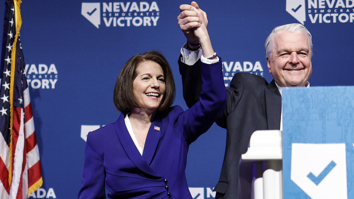 Sen. Catherine Cortez Masto, D-N.V., and Nevada Gov. Steve Sisolak hold their hands up after giving remarks at an election night party.