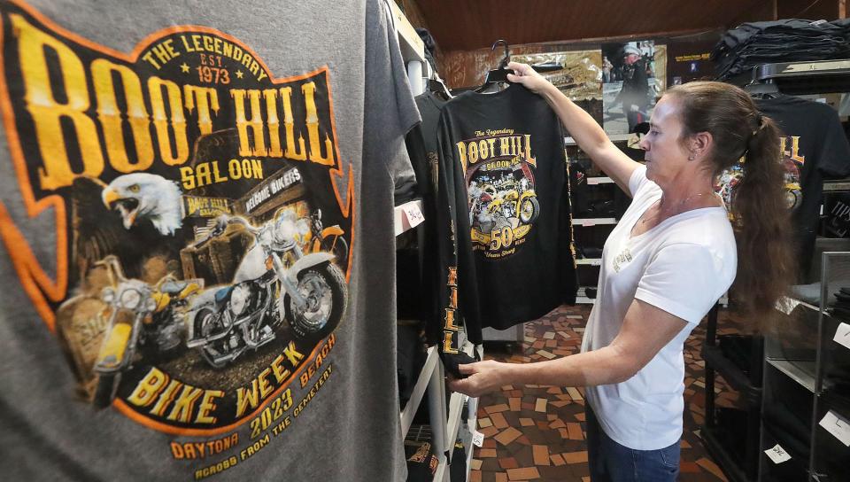 A Boot Hill Saloon employee hangs commemorative T-shirts in the bar's souvenir shop ahead of its 50th anniversary celebration in 2023.