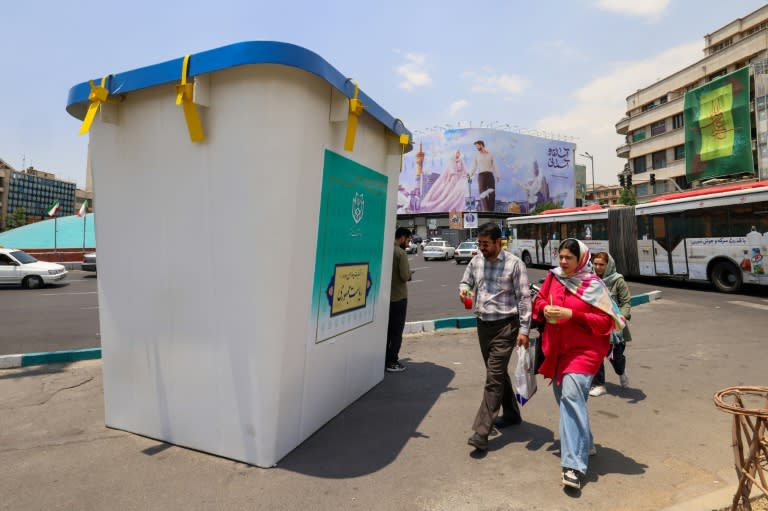 People walk past a replica of a ballot box installed on a street in Tehran (Atta KENARE)