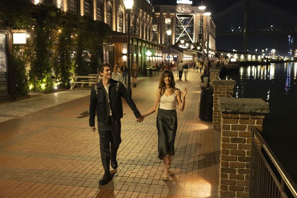 a man and woman walking on a bridge at night