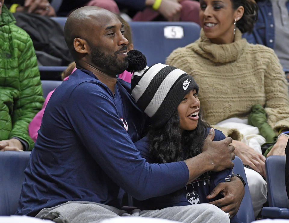 FILE - In this March 2, 2019, file photo, Kobe Bryant and his daughter Gianna watch the first half of an NCAA college basketball game between Connecticut and Houston in Storrs, Conn. Autopsy reports released Friday, May 15, 2020, show that the pilot who flew Bryant did not have drugs or alcohol in his system when the helicopter crashed in Southern California in January, killing all nine aboard. The causes of death for Bryant, his 13-year-old daughter Gianna, pilot Ara Zobayan and the others have been ruled blunt force trauma. Federal authorities are still investigating the Jan. 26 incident where the chopper crashed into the Calabasas hillsides. (AP Photo/Jessica Hill, File)