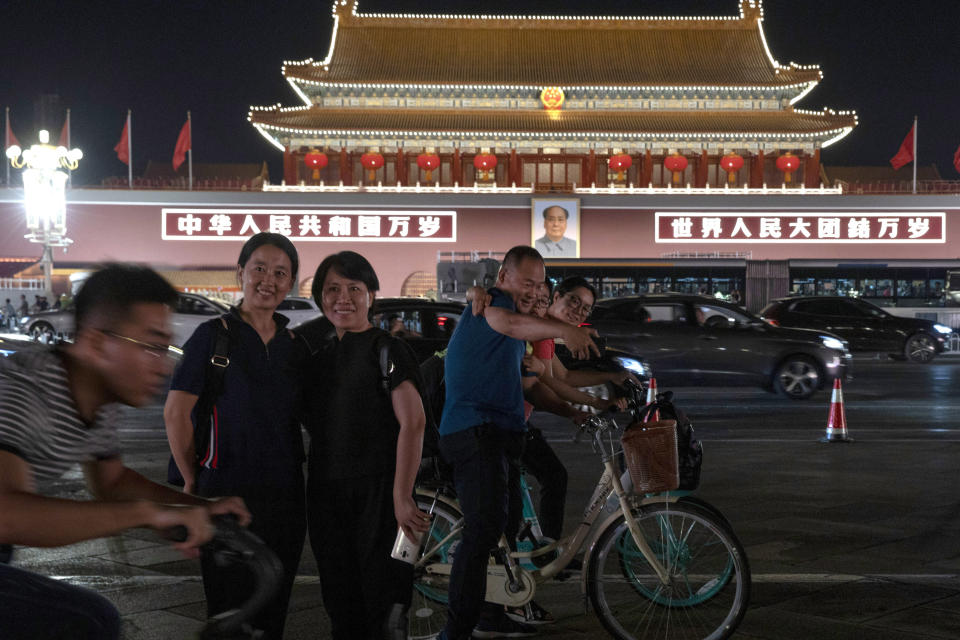 In this Saturday, Sept. 28, 2019, photo, Chinese visitors pose for photos near Tiananmen gate which is prepared for the upcoming 70th anniversary of the Founding of the People's Republic of China in Beijing. Chinese President Xi Jinping has an ambitious goal for China: to achieve "national rejuvenation" as a strong and prosperous nation by 2049, which would be the 100th anniversary of Communist Party rule. One problem: U.S. President Donald Trump wants to make the United States great again too. (AP Photo/Ng Han Guan)