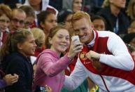 Greg Rutherford of England poses for a photograph with his gold medal after winning the men's long jump final at the 2014 Commonwealth Games in Glasgow, Scotland, July 30, 2014. REUTERS/Phil Noble