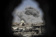 <p>A bomb explodes behind the al-Nuri mosque complex, as seen through a hole in the wall of a house, as Iraqi Special Forces move toward Islamic State militant positions in the Old City of Mosul, Iraq, Thursday, June 29, 2017. (Photo: Felipe Dana/AP) </p>