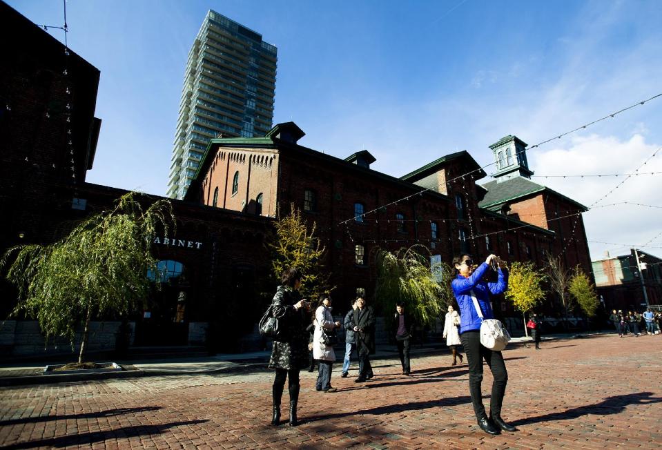 This Nov. 14, 2012 photo shows people taking photographs as they walk around at the historical Distillery District in Toronto. This quaint East End area has been turned into an enclave of art galleries, restaurants and boutiques offering one-of-a-kind fare such as hand-crafted jewelry housed in restored heritage Victorian buildings. (AP Photo/The Canadian Press, Nathan Denette)