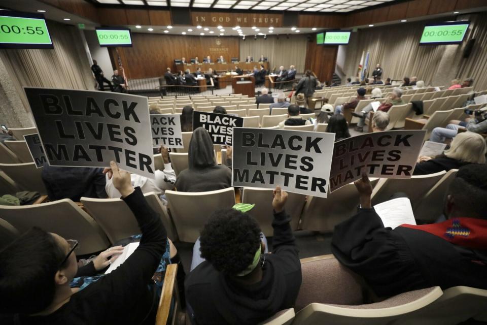Protesters with signs at a Torrance City Council meeting after a police shooting