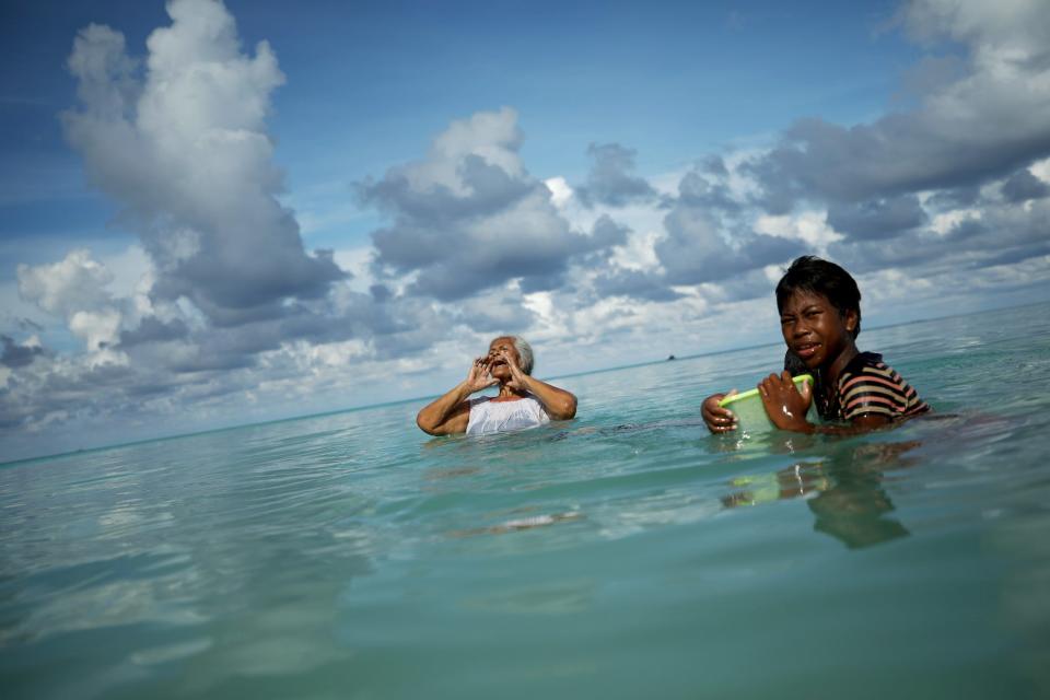Suega Apelu (C) calls out to a family member as Tina Makiti looks on as they swim in the lagoon on November 28, 2019 in Funafuti, Tuvalu.