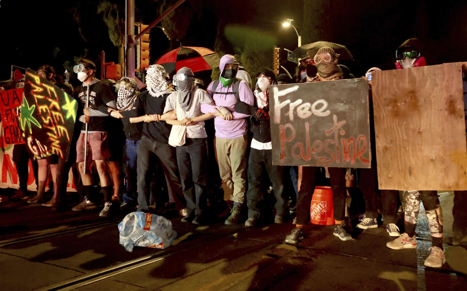 Demonstrators lock arms near the intersection of Park Avenue and University Boulevard as they confront law enforcement officers, Friday, May 10, 2024, Tucson, Az. (Kelly Presnell/Arizona Daily Star via AP)