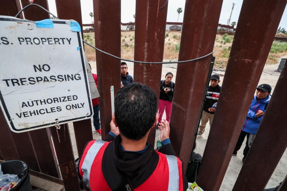 Pedro Rios of the American Friends Service Committee talks with asylum seekers at the border near San Diego in June.