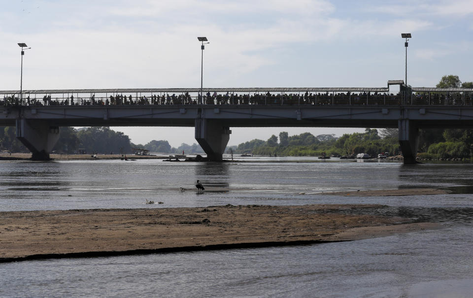 Migrants crowd the the bridge spanning the Suchiate River on the border between Guatemala and Mexico in Ciudad Hidalgo, Saturday, Jan. 18, 2020. More than a thousand Central American migrants surged onto the bridge as Mexican National Guardsmen attempted to impede their journey north. (AP Photo/Marco Ugarte)