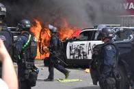 A police car burns as another one is seen destroyed during a protest over the death of George Floyd Saturday, May 30, 2020, in Los Angeles. Floyd died in police custody on May 25 in Minneapolis. (AP Photo/Mark J. Terrill)