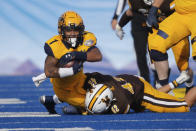 Kent State running back Marquez Cooper (1) stretches for an extra yard as he is tackled by Wyoming safety Isaac White (42) during the first half of the Idaho Potato Bowl NCAA college football game, Tuesday, Dec. 21, 2021, in Boise, Idaho. (AP Photo/Steve Conner)