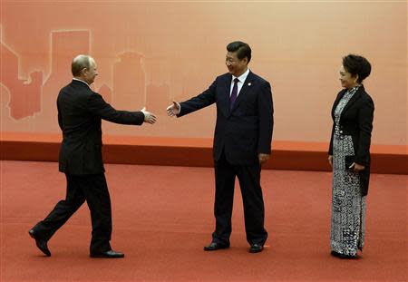 Russian President Vladimir Putin (L) is greeted by the Chinese President Xi Jinping (C) and his wife Peng Liyuan before the group photo event at the fourth Conference on Interaction and Confidence Building Measures in Asia (CICA) summit in Shanghai May 20, 2014. REUTERS/Mark Ralston/Pool