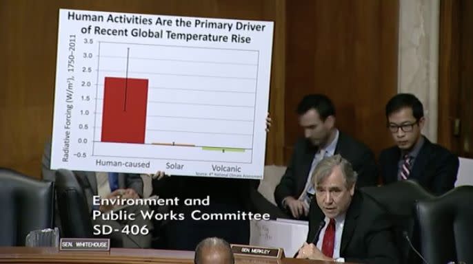 A staffer for&nbsp;Sen. Jeff Merkley (D-Ore.) holds up a sign citing data from the&nbsp;federal government's latest climate&nbsp;change report, released by the Trump administration. (Photo: Senate EPW)