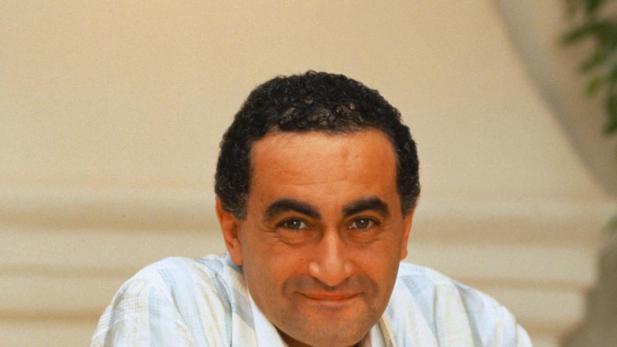 dodi fayed smiles at the camera and wears a blue, white and cream plaid jacket over a white collared shirt