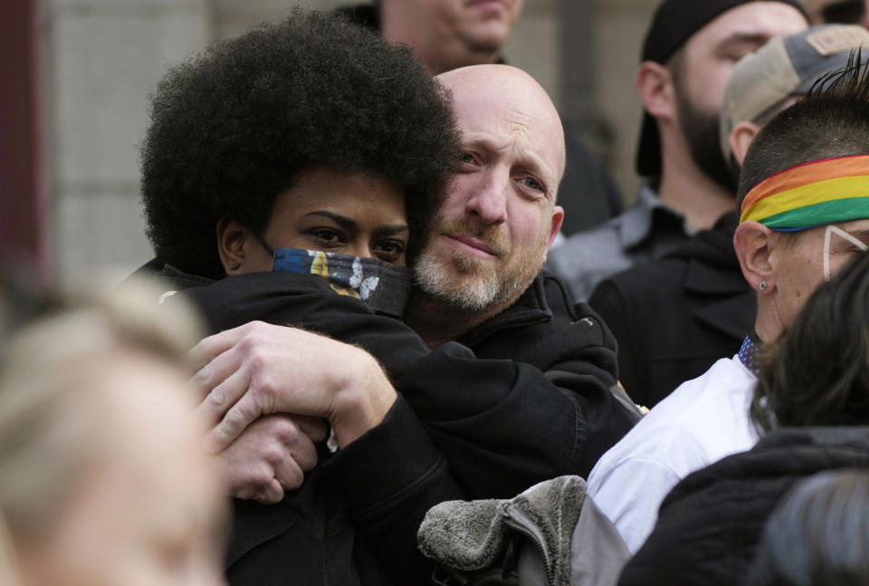 Nic Grzecka, right, co-owner of Club Q, hugs a supporter after a 25-foot historic pride flag was unfurled to cover the exterior of City Hall to mark the weekend mass shooting at the gay nightclub Wednesday, Nov. 23, 2022, in Colorado Springs, Colo. The flag, known as Section 93 of the Sea to Sea Flag, is on loan for two weeks to Colorado Springs from the Sacred Cloth Project. (AP Photo/David Zalubowski)