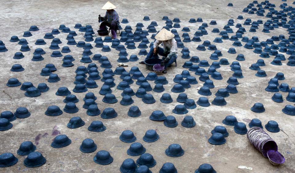 Women paint paper replicas of soldier's hats for the Vu Lan Festival at Dong Ho village, outside Hanoi