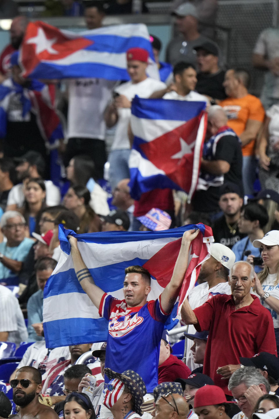 Cuba fans wave Cuban flags as the cheer during the first inning of a World Baseball Classic game between Cuba and the U.S., Sunday, March 19, 2023, in Miami. (AP Photo/Wilfredo Lee)