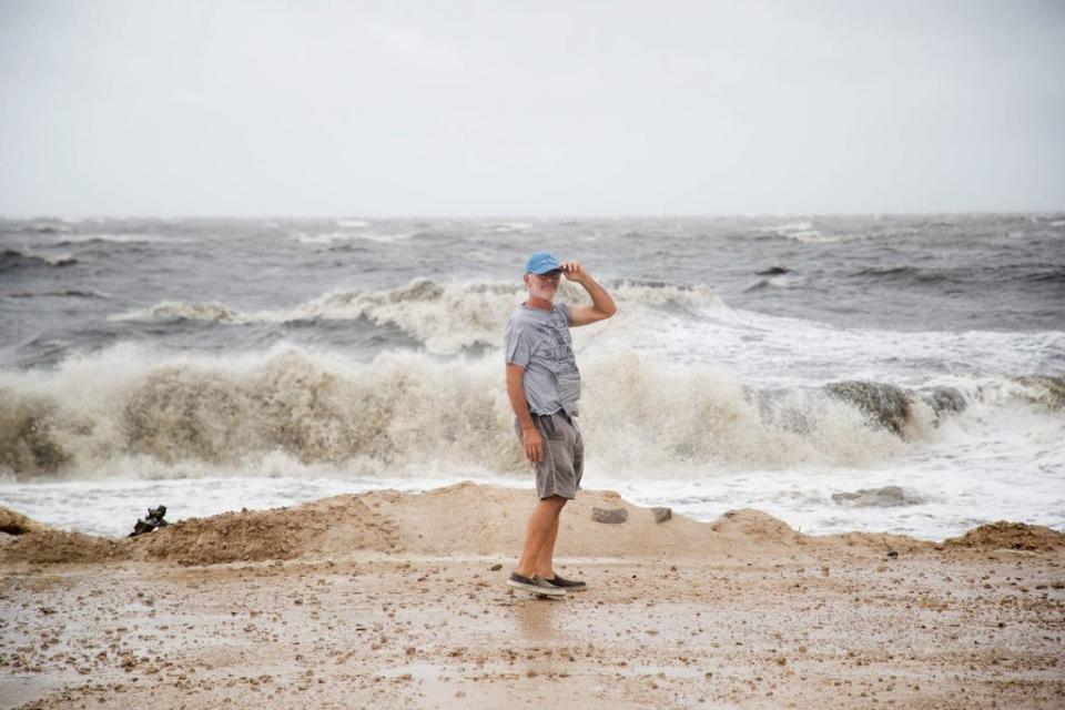 A man holds tight to his hat as he walks along the water in Alligator Point, Fla. as Tropical Storm Fred brings strong winds and rain to Florida's Forgotten Coast on Monday, August 16, 2021.