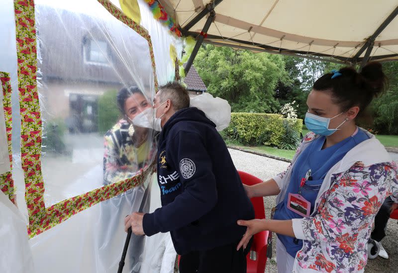Residents at Belgian nursing home "Le Jardin de Picardie" enjoy hugs and cuddle through a wall made with plastic sheets to protect against potential COVID-19 infection in Peruwelz