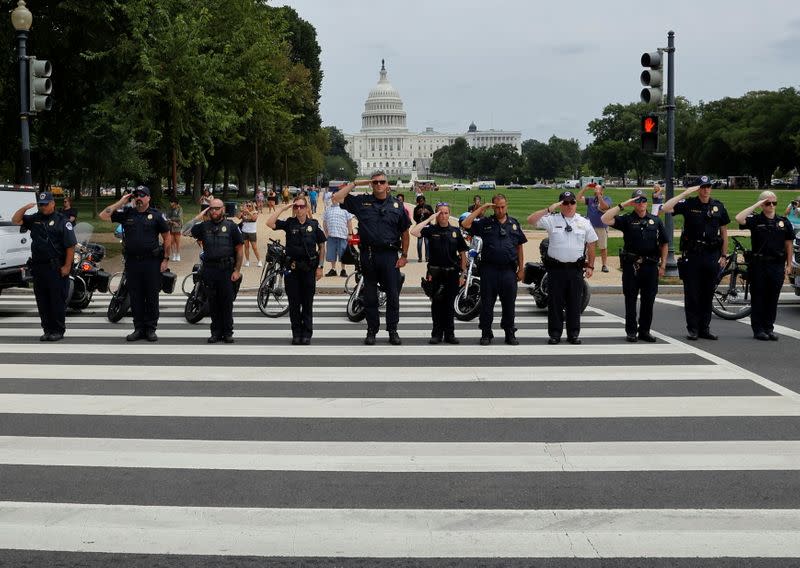 FILE PHOTO: Law enforcement officers salute as a ceremonial procession in honor of a police officer wounded at the Pentagon passes the U.S. Capitol in Washington