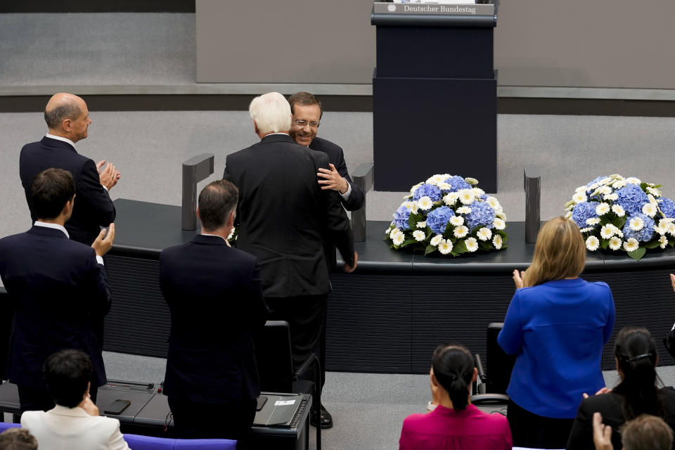Israeli President Isaac Herzog, right, embarances German President Frank-Walter Steinmeier as he receives standing ovations after his speech at the German parliament Bundestag at the Reichstag building in Berlin, Germany, Tuesday, Sept. 6, 2022. Left are German Chancellor Olaf Scholz. (AP Photo/Markus Schreiber)