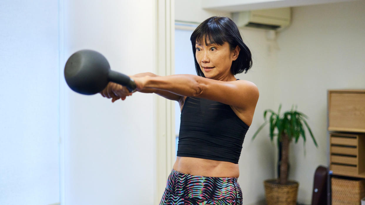  A woman performing a kettlebell swing at home  