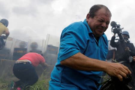 An opposition supporter runs away from tear gas in front of Venezuelan National Guards during a rally to demand a referendum to remove President Nicolas Maduro in Caracas, Venezuela June 7, 2016. REUTERS/Marco Bello