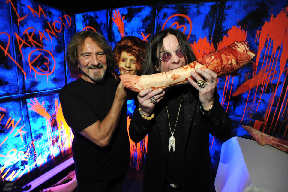 In this Tuesday, Sept. 17, 2013 photo, Geezer Butler, left, and Ozzy Osbourne pose with props at the "Black Sabbath: 13 3D" maze at Universal Studios Halloween Horror Nights, in Universal City, Calif. While on a behind-the-scenes trek through a Universal Studios Hollywood attraction based on the recently released Black Sabbath album "13," Osbourne spots a bloody mannequin corpse reclining on a phony altar. Without hesitating, the gruesomely theatrical Sabbath frontman leans down and acts like he's devouring the blood from the decapitated body. (Photo by John Shearer/Invision/AP)