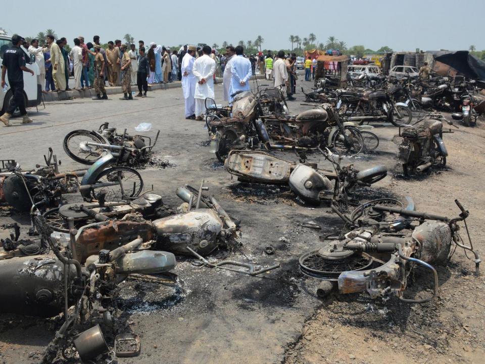 People gather behind burnt motorcycles and vehicles at the scene of the accident on the outskirts of Bahawalpur (EPA/Faisal Kareem)