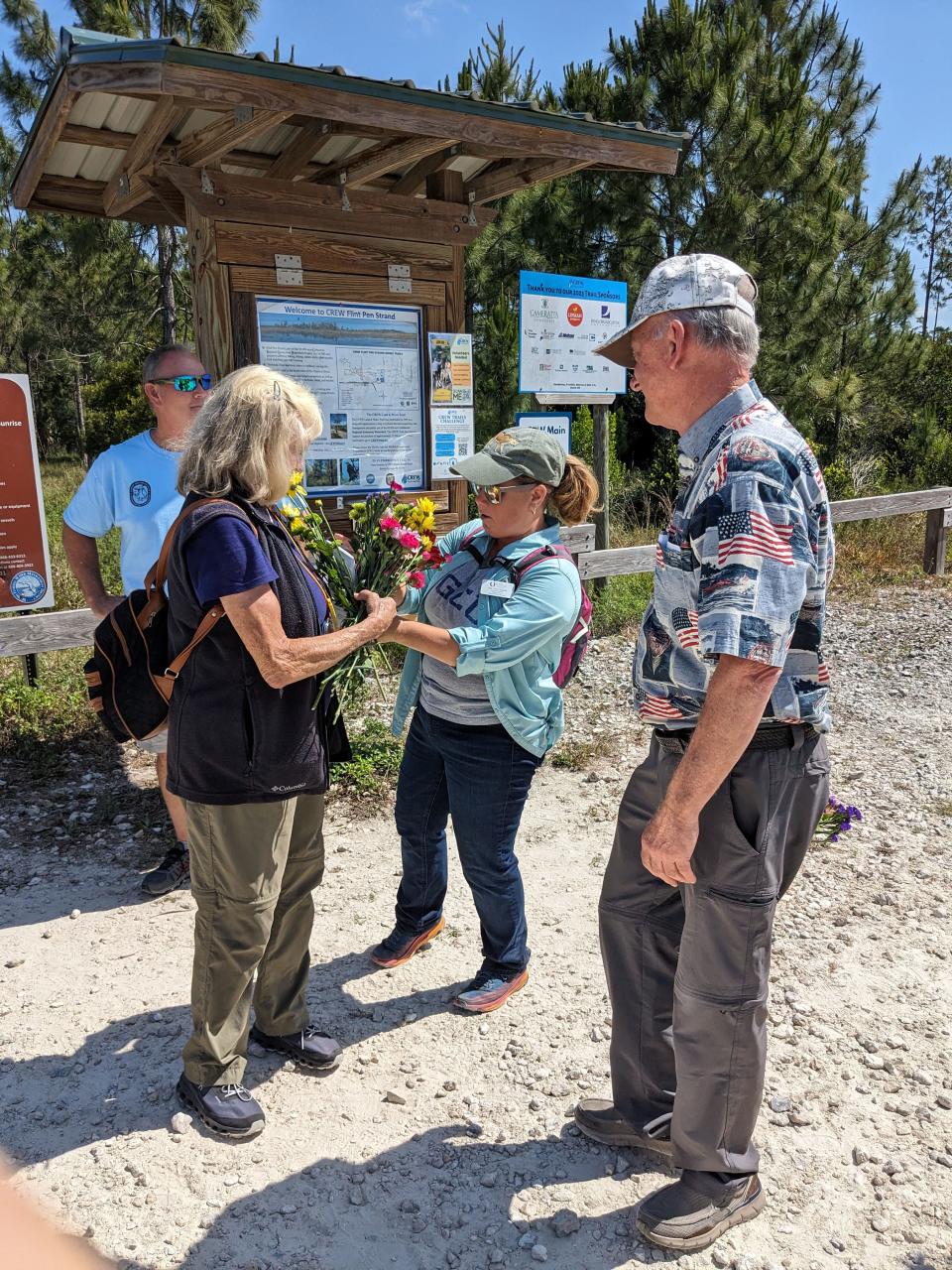 Ann Godsea, Education Director Wings of Hope, hands Ricky Pires flowers just after she left the CREW trail with the Panther Posse for the last time. Ben Nottingham, the former director of the Panther Preserve, was also there to greet her.