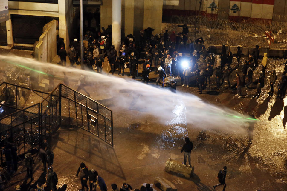 Riot police sprayed anti-government protesters with water cannons as they try to cross to the central government building during ongoing protests in Beirut, Lebanon, Saturday, Jan. 25, 2020. Hundreds of Lebanese gathered outside the central government building to reject the newly formed Cabinet, while some protesters breached tight security erected around it, removing a metal gate and barbed wire prompting a stream of water cannons from security forces. (AP Photo/Bilal Hussein)