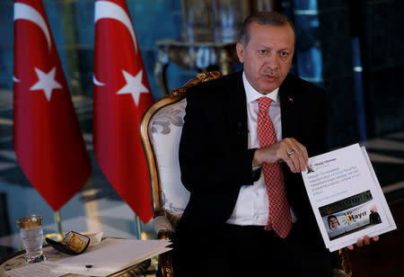 Turkish President Tayyip Erdogan shows a document as he attends an interview with Reuters at the Presidential Palace in Ankara, Turkey, April 25, 2017. REUTERS/Umit Bektas