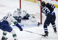Vancouver Canucks goaltender Thatcher Demko (35) makes a save against Winnipeg Jets' Sean Monahan (23) as Nikita Zadorov (91) defends during the second period of an NHL hockey game Thursday, April 18, 2024, in Winnipeg, Manitoba. (John Woods/The Canadian Press via AP)