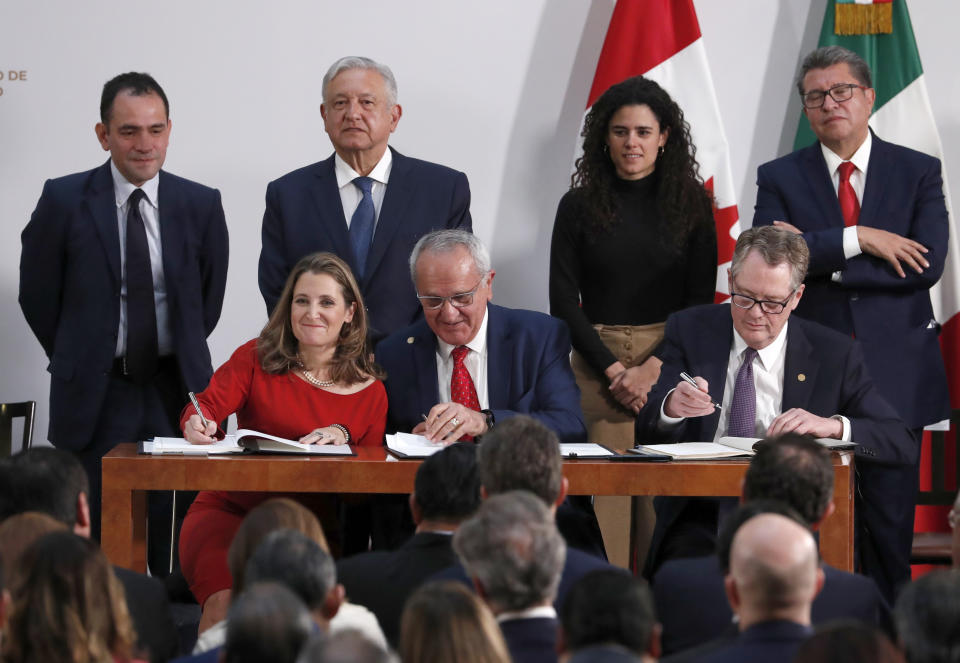 Deputy Prime Minister of Canada Chrystia Freeland, left, Mexico's top trade negotiator Jesus Seade, center, and U.S. Trade Representative Robert Lighthizer, sign an update to the North American Free Trade Agreement, at the national palace in Mexico City, Tuesday, Dec. 10. 2019. Observing from behind are Mexico's Treasury Secretary Arturo Herrera, left, Mexico's President Andres Manuel Lopez Obrador, second left, Mexico's Labor Secretary Maria Alcade, third left, and The President of the Mexican Senate Ricardo Monreal. (AP Photo/Marco Ugarte)