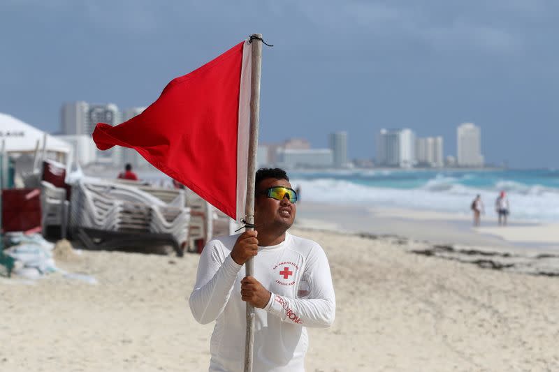 A lifeguard places a red flag on the beach to warn beachgoers of hazards due to the proximity of Hurricane Zeta in Cancun