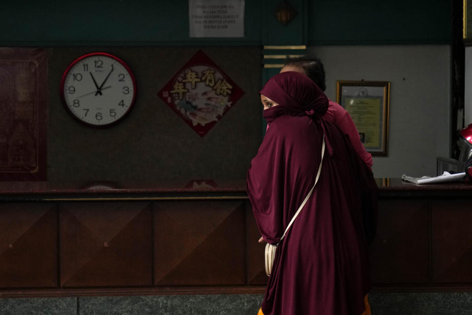 A refugee stands in front of what used to be the reception desk of Hotel Kolekta, turned into a shelter for refugees, in Batam, an island in northwestern Indonesia, Thursday, May 16, 2024. The former tourist hotel was converted in 2015 into a temporary shelter that today houses 228 refugees from conflict-torn nations including Afghanistan, Somalia, Sudan and elsewhere. (AP Photo/Dita Alangkara)