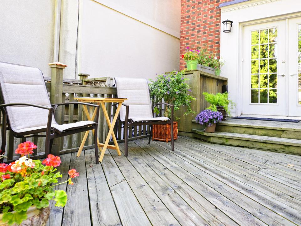 simple back porch with flowers and two chairs and a small table